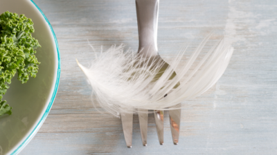 En vit liten fjäder ligger på en gaffel.