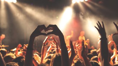 Människor på en konsert sträcker upp sina händer och formar ett hjärta