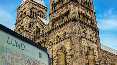 Lunds domkyrka bakom en stadskarta över staden. Himlen är klarblå.