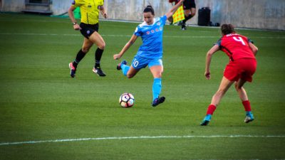 En fotbollsspelare i blåa kläder sparkar på en fotboll