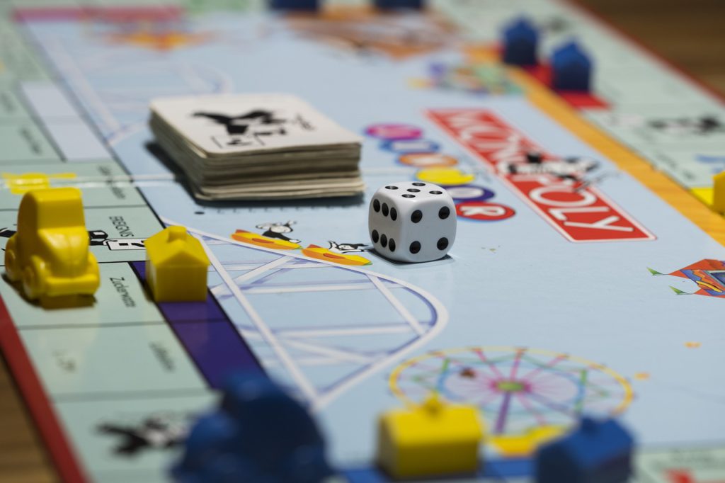Monopolbräde med hus och kort och en tärning på.