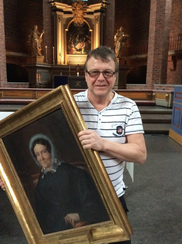 Man i en kyrka med en tavla i handen