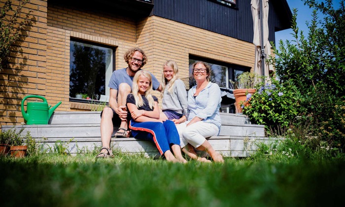Skånsk familj sitter framför sitt hus