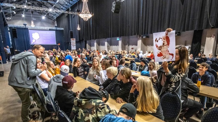 Människor sitter runt massa bord och väntar på workshop