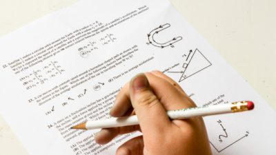 En hand håller en penna ovanför ett mattetest