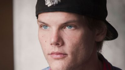 Porträttbild av Avicii. Han har rutig skjorta och en keps bakochfram. Han ser ut att vara ungefär 20 och ser allvarlig ut.
