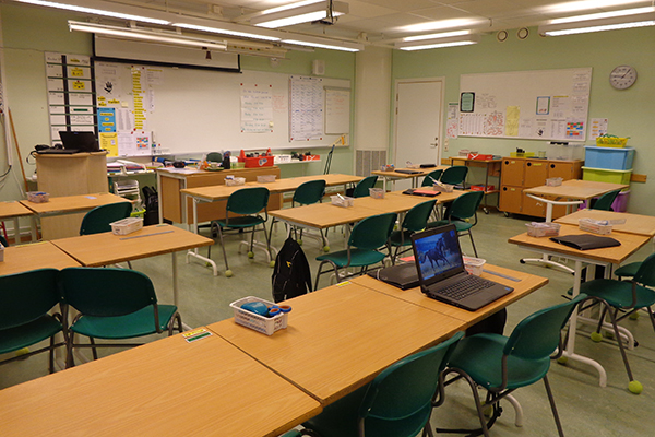 Bänkar på rad i ett klassrum med lysrör i taket.