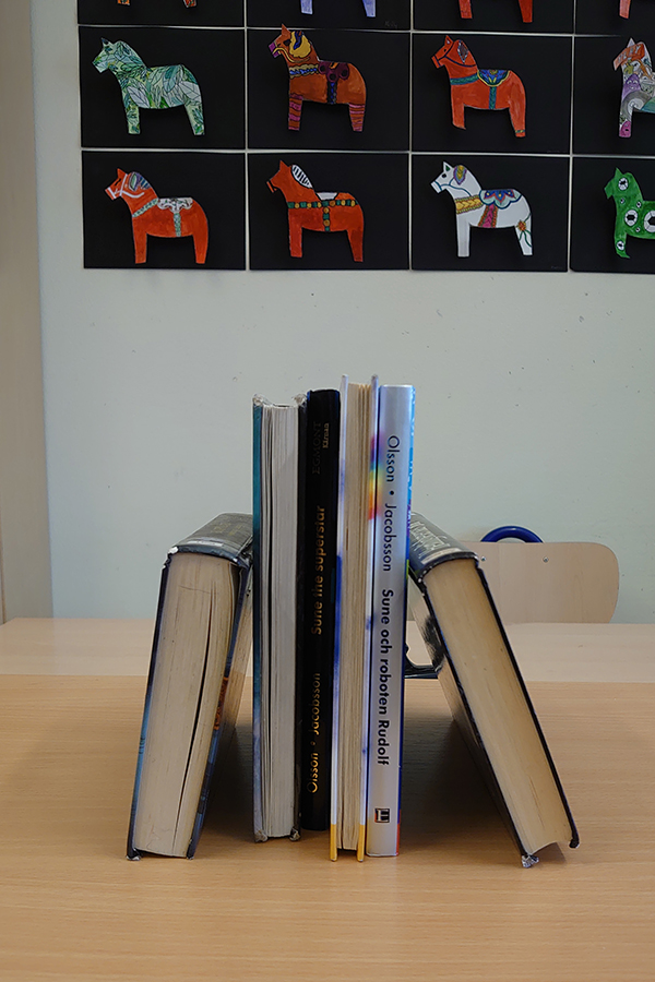 Foto på ett gäng böcker uppställda på en bänk.