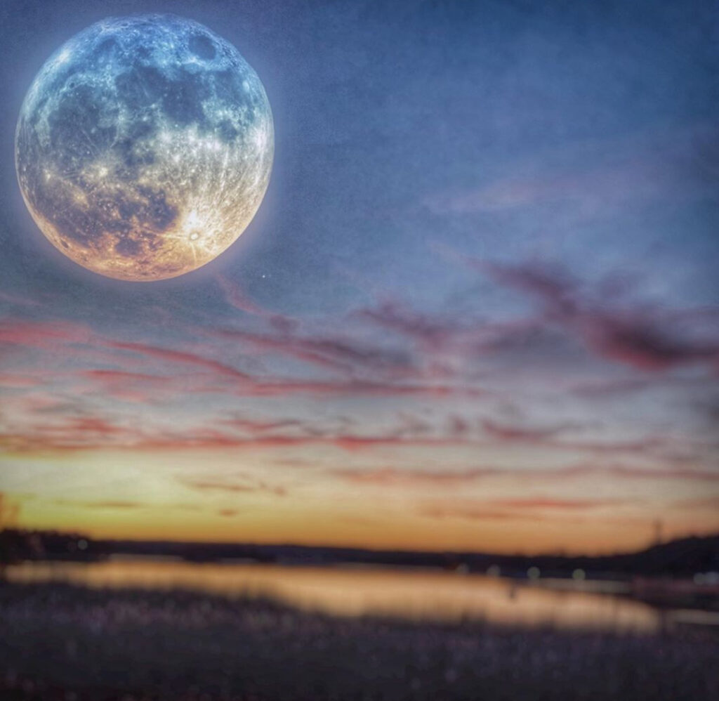 En solnedgång och en stor måne som svävar på himlen.