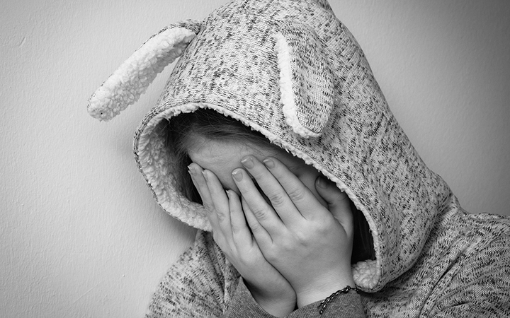 Ett barn som gömmer ansiktet i händerna.